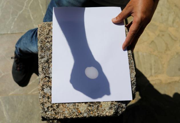 A man uses a telescope to plan the reflection of the sun, highlighting the partial eclipse seen in Rhne, Spain on June 10, 2021.